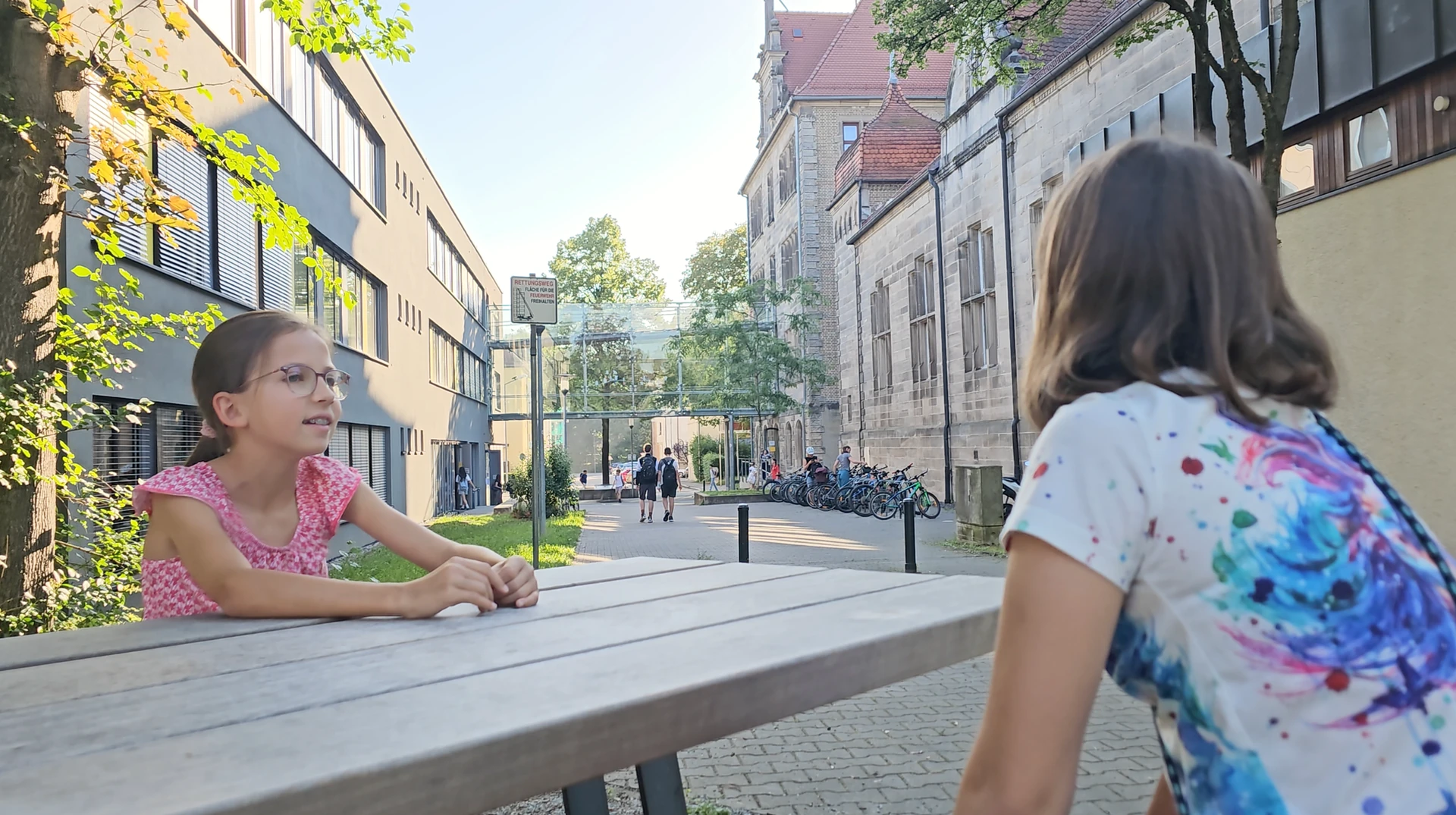 Zwei Schüler unterhalten sich am Tisch auf dem Schulhof