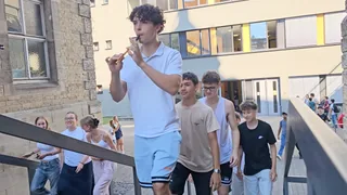 Ein Schüler spielt Flöte, während eine Gruppe die Außentreppe hinaufgeht.