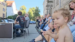 Publikum bei einem Konzert vor dem Schulgebäude.