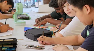 Schüler zeichnen gemeinsam an einem Tisch.