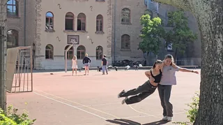 Zwei Schülerinnen spielen auf dem Sportplatz vor dem Altbau.