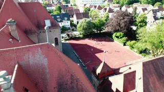 Der Sportplatz zwischen roten Dächern und Bäumen aus der Luft.