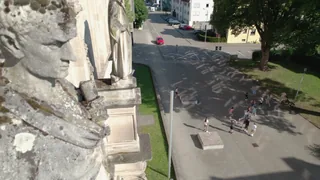 Eine steinerne Fassadenfigur über dem belebten Schulhof.