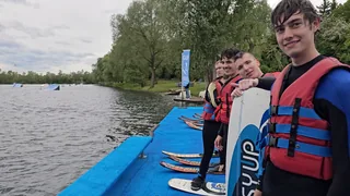 Schüler mit Schwimmwesten und Wasserskiausrüstung am See.