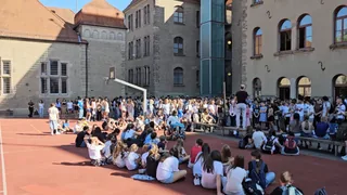 Die Schulgemeinschaft versammelt sich auf dem Sportplatz.
