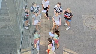 Schülerinnen winken zur Kamera oberhalb der Glasbrücke.
