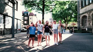 Eine Gruppe Schülerinnen winkt auf dem Schulhof.