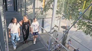 Drei Schülerinnen gehen über die gläserne Brücke.
