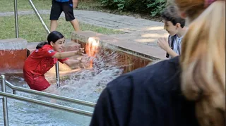 Kinder spritzen einander lachend mit Wasser nass.