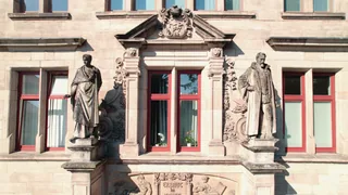 Cicero- und Kepler-Figuren an der Sandsteinfassade der Schule.