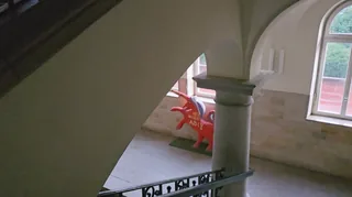 Bögen und Säule im Treppenhaus mit einer roten Einhornfigur.