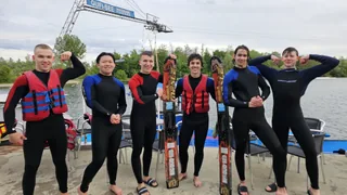 Eine Schülergruppe mit Wasserskiausrüstung steht gemeinsam am See.