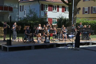 Schülerinnen und Schüler musizieren auf einer Bühne im Freien.