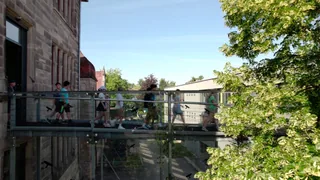 Schülerinnen und Schüler überqueren die gläserne Brücke zwischen den Schulgebäuden.