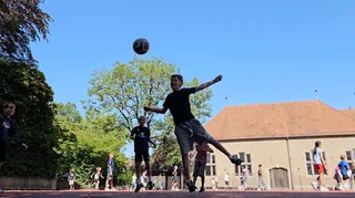 Ein Schüler springt auf dem Schulhof nach einem Fußball.