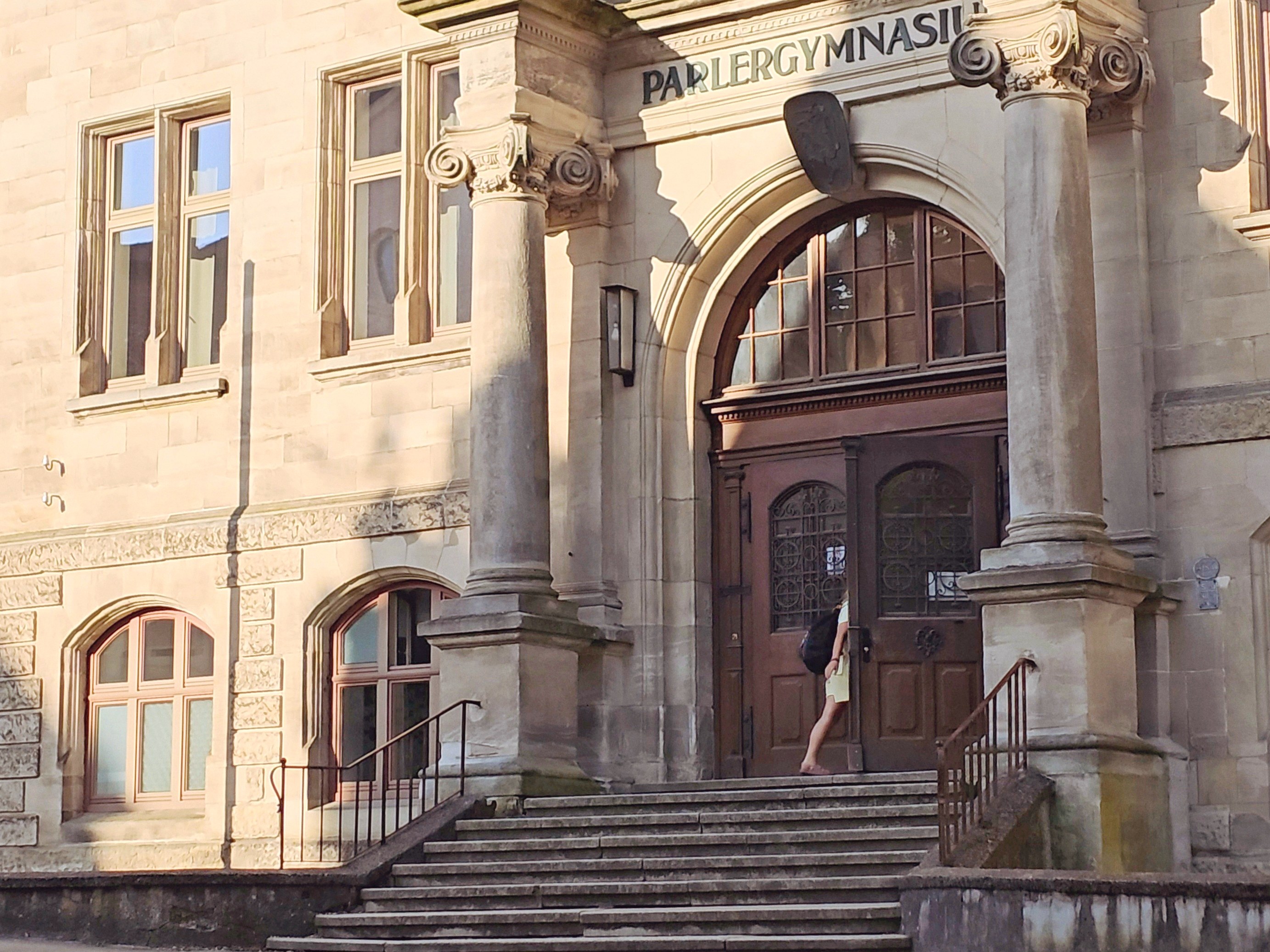 Historischer Haupteingang des Parler-Gymnasiums mit Treppe und Säulen.