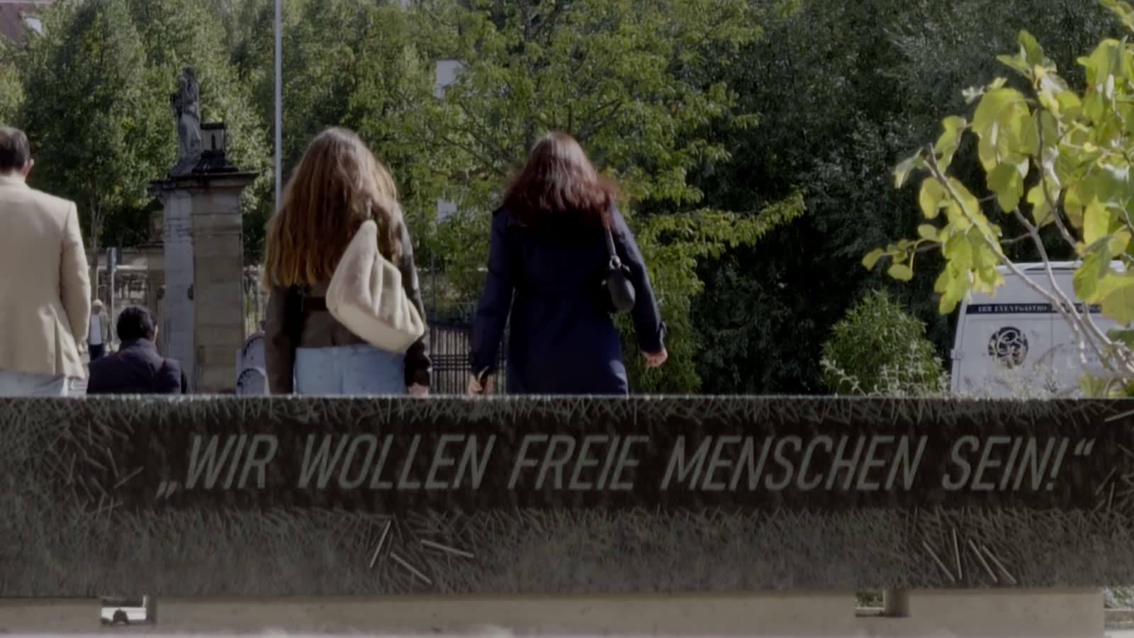 Der Gmünder Gedenkstein mit der Inschrift „Wir wollen freie Menschen sein!“; dahinter gehen junge Menschen durch den Park.